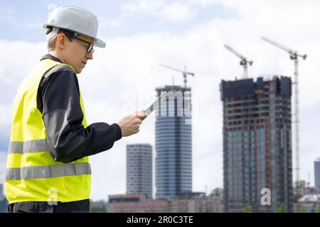 Engineer with a digital tablet on the background of a building under construction. High quality photo Stock Photo