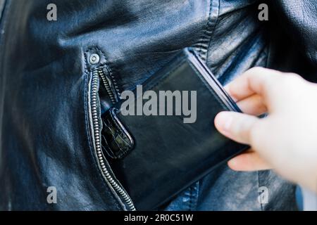 From the pocket of jacket the thief pulls out card banknote money purse wallet. Stock Photo