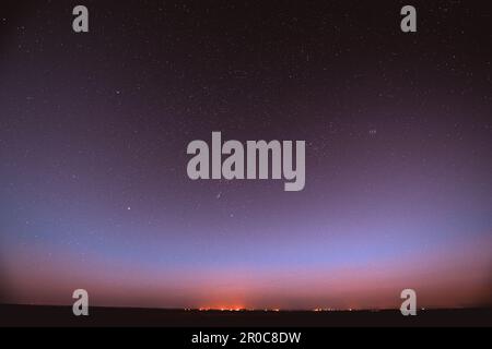 Night Violet Sky Glowing Stars Background Backdrop With Sky Gradient. Colorful Night Starry Sky In Blue Colors. Amazing Night View Sky Above Village Stock Photo