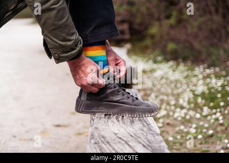 walker man tying his shoes - close up of a pair of sneakers on a wooden plank Stock Photo