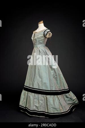 Two-piece Evening Dress, 1868.  Taffeta two-piece dress with velvet ribbon and lace trim. The skirt has a train. Stock Photo