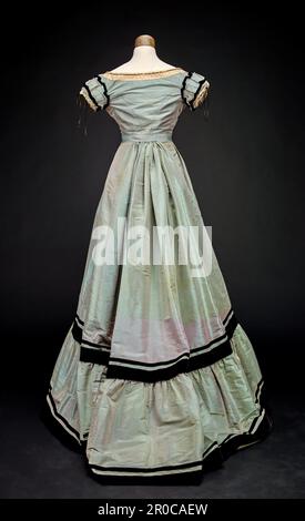 Two-piece Evening Dress, 1868.  Taffeta two-piece dress with velvet ribbon and lace trim. The skirt has a train. Stock Photo