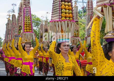 Denpasar, Bali island, Indonesia - June 11, 2016: Procession of beautiful Balinese women in traditional costumes - sarong, carry offering on heads Stock Photo