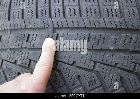 Checking the tire tread with the help of tread indicators in a close-up Stock Photo