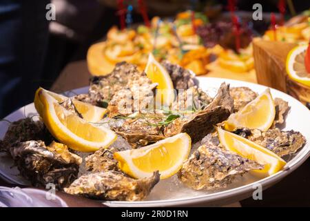 Close-up of oysters on a plate with lemon slices at a fish festival on a sunny day, selected focus Stock Photo