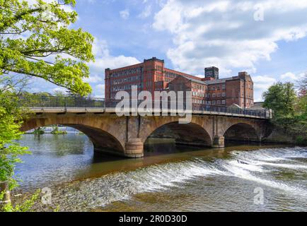 Belper Derbyshire Bridge Foot bridge over the River Derwent with small weir and Strutts North Mill Belper Derbyshire UK GB Europe Stock Photo