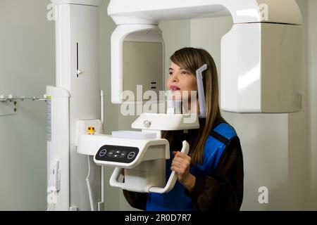 Female patient having computer tomography of jaw, circular snapshot of jaw in modern dentistry in x-ray office. Computed 3d tomography of teeth and ja Stock Photo