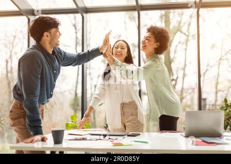 Three Coworkers Giving High Five Sharing Business Success In Office Stock Photo