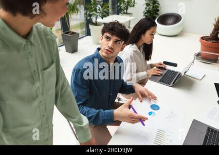 Young Middle Eastern Man Consulting With Colleague In Modern Office Stock Photo