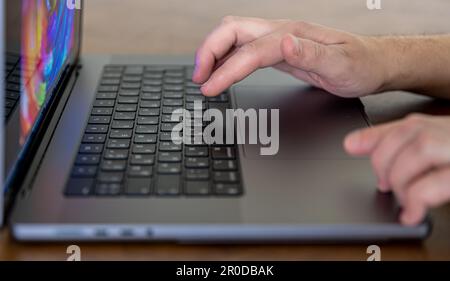 Close-up, male hands are typing on the keys of a laptop. Stock Photo