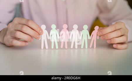Holding paper human figures on light blue background, closeup with space for text. Diversity and inclusion concept Stock Photo