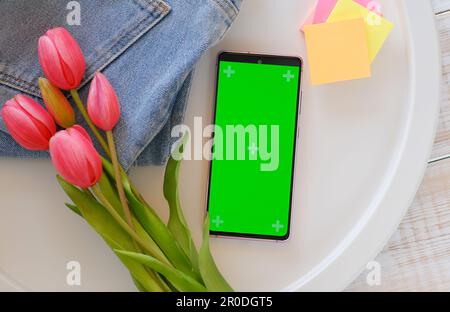 flowers on the table and smartphone with green screen mock up for flower delivery. ordering flowers online Stock Photo
