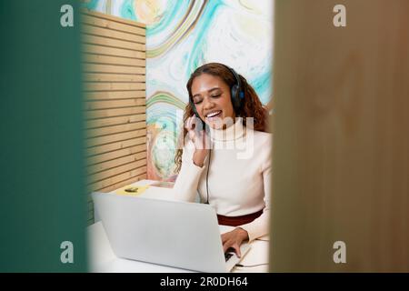 Shot of young office worker sitting in private booth, on remote call headset Stock Photo