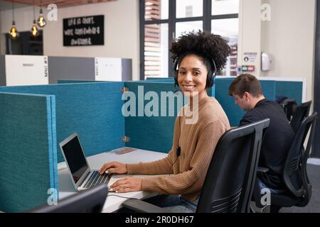 Portrait of multi-ethnic woman, working next to colleague in office Stock Photo