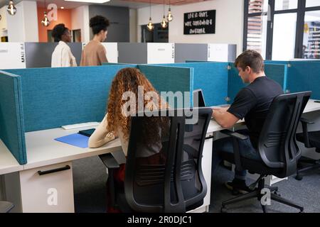 Four diverse coworkers in a modern open plan office, desk dividers, creative Stock Photo