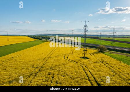 Aerial view of electricity pylons with power lines over agricultural field. Stock Photo
