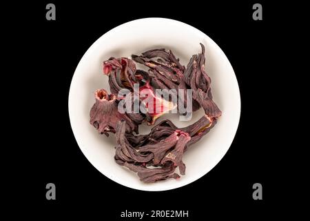 Dry aromatic karkade tea with a white saucer on a black background, macro, top view. Stock Photo