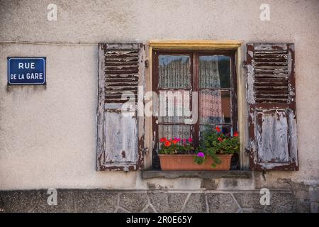 Geraniums in a window box with open shutters and a road name sign, Apach, France (tri-border area) Stock Photo