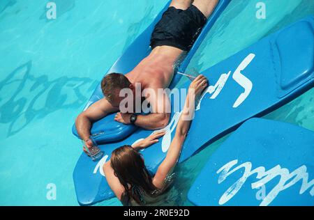 Couple swimming on airbeds, Sandals Halcyon Beach Resort, St. Lucia, Caribbean Stock Photo