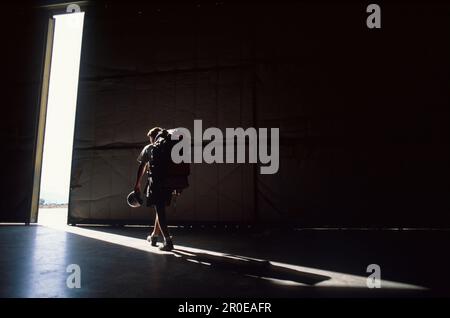 skydiver goes out into the freedom through a hall, packpack, boots and helmet Stock Photo