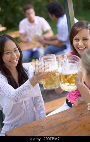 Three young women, friends, having fun in a beer garden, lake Starnberg See, Bavaria, Germany Stock Photo