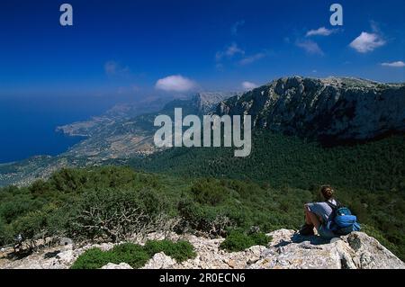 Woman sitting on rock, looking at view, Serra de Tramuntana, Majorca, Spain Stock Photo