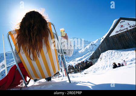 Woman in deck chair, St. Christoph, Woman with drink sitting on deck chair in the snow, St. Anton at Arlberg, Tyrol, Austria Stock Photo