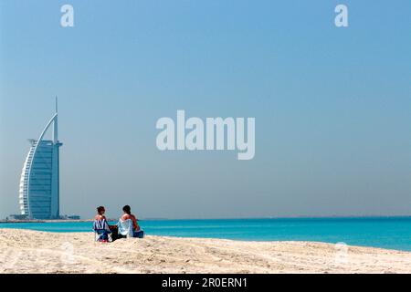 View at a couple on the beach and the Burj al Arab hotel, Dubai, United Arab Emirates, Middle East, Asia Stock Photo