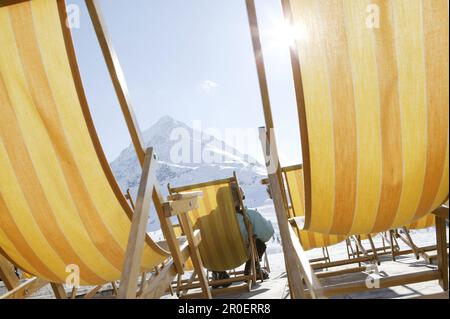 Person relaxing in deck chair, mountain Hohe Mut in background, Kuhtai, Tyrol, Austria Stock Photo