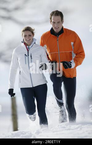 Young couple running on snow Stock Photo