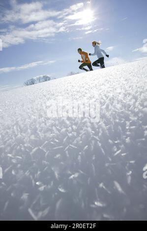 Young couple running through deep snow Stock Photo