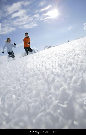 Young couple running through deep snow Stock Photo