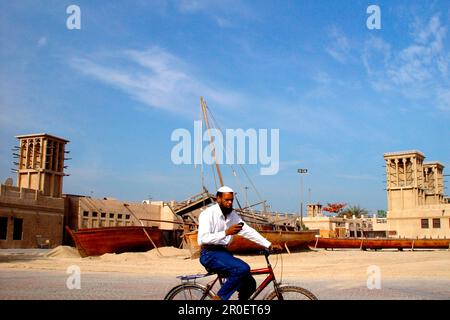 Man on bicycle with mobile, Bur Dubai, Dubai, United Arab Emirates, UAE Stock Photo