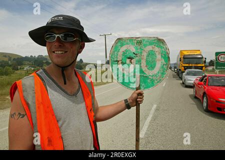 Roadworker holding stop and go sign, New Zealand, Oceania Stock Photo