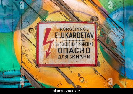 Old and rusty soviet-era warning sign of high voltage electricity on a colorful wooden door in Telliskivi district of Tallinn, Estonia Stock Photo