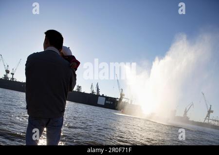 Father holding baby, looking from quay, river Elbe, harbor and docks, St. Pauli, Hamburg, Germany Stock Photo