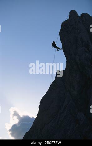 Silhouette of man climbing rock face, side view, Alpspitze, Bavaria, Germany Stock Photo