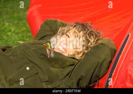 Young woman with a blond curly hair lying in the sun and smiling Stock Photo