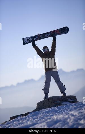 Person lifting up a snowboard, mountain chain in the background, Kuehtai, Tyrol, Austria Stock Photo