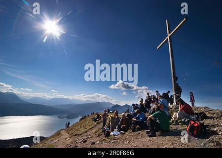 Large group of hikers looking from Jochberg summit onto Lake Walchensee, Upper Bavaria, Germany Stock Photo