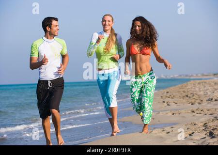 Three young people jogging on beach, Apulia, Italy Stock Photo
