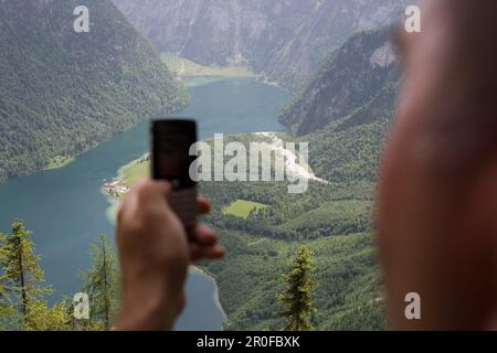 Man photographing Lake Koenigssee using his Mobile Phone, Near Watzmann Mountain, Berchtesgaden, Berchtesgadener Land, Bavaria, Germany Stock Photo
