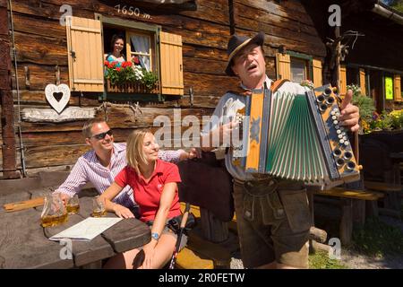 People listening to man playing accordion, Lammersdorf hut, Lammersdorf near Millstatt, Carinthia, Austria Stock Photo