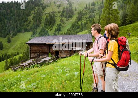 Couple hiking, arriving at Karseggalm, 1603 m, one of the oldest mountain huts in the valley, Grossarl Valley, Salzburg, Austria Stock Photo