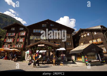 Two snowboarder passing a souvenir shop at Bahnhofplatz, Zermatt village, Zermatt, Valais, Switzerland Stock Photo