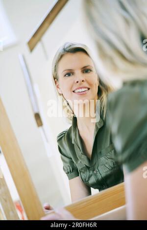 Young woman looking into the mirror, reflected in the mirror Stock Photo