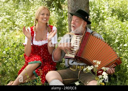 Mature man playing melodeon, woman clapping hands Stock Photo