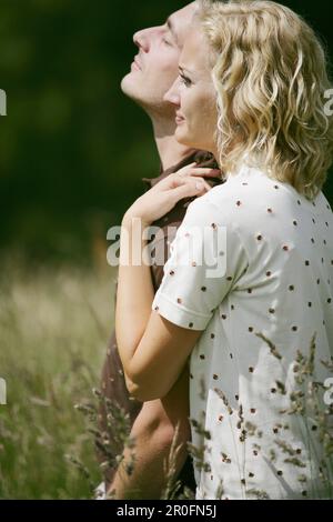 Young couple standing in mountain pasture, Heiligenblut, Hohe Tauern National Park, Carinthia, Austria Stock Photo