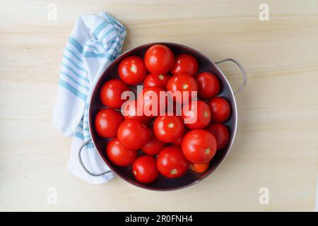 Ripe fresh tomatoes in an iron bowl on a wooden table, close-up Stock Photo