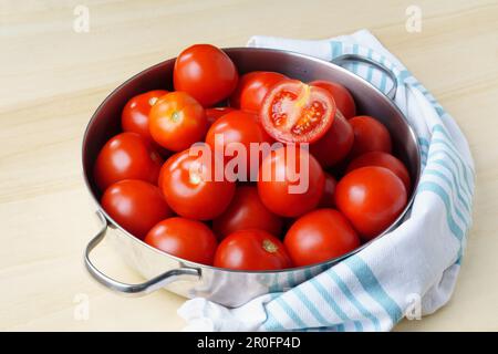 Ripe fresh tomatoes in an iron bowl on a wooden table, close-up Stock Photo